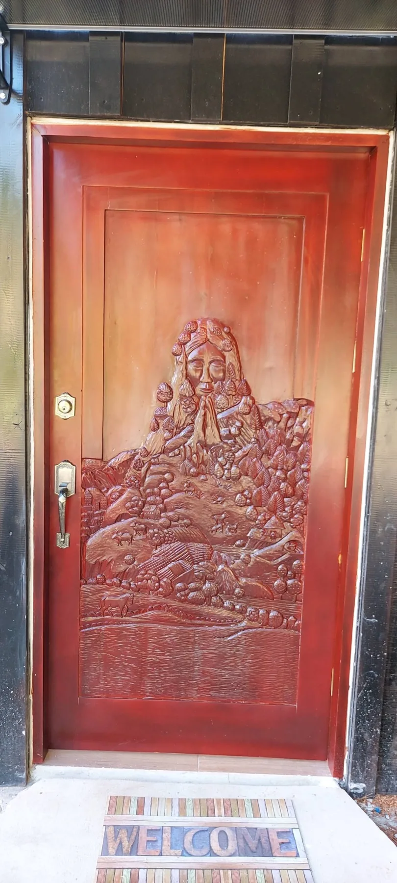 Hand-carved wooden front door depicting Pachamama