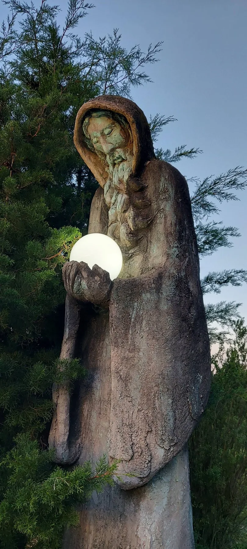 Hooded stone sculpture holding a glowing orb
